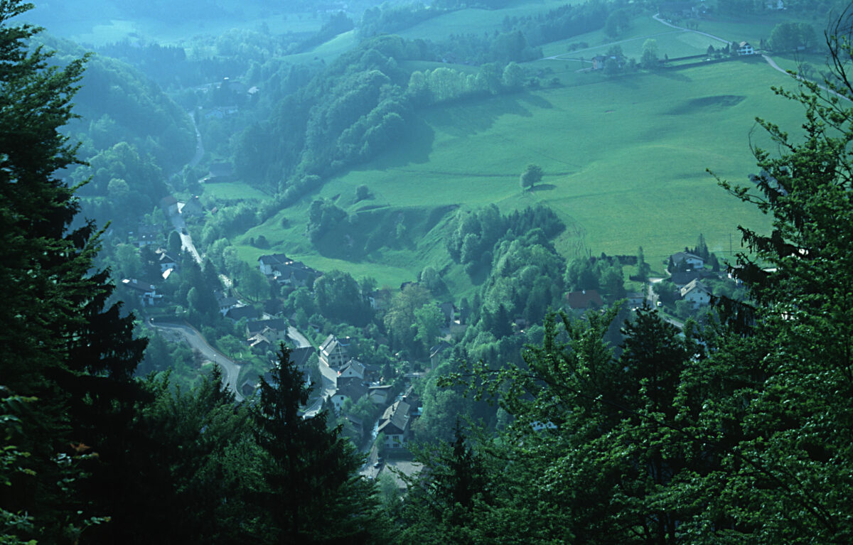 Blick in die Talschlucht auf Siedlung mit Serpentinenstraße und dahinter Hügellang am Kreuzberg
